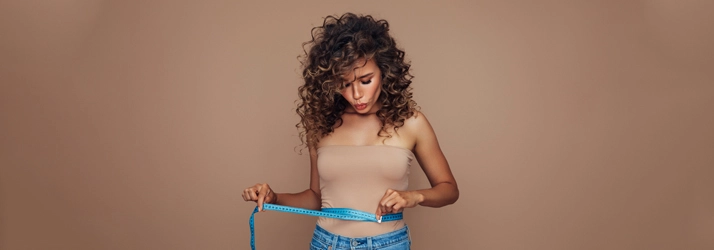 Chiropractic Ocoee FL Body Contouring A woman holding a blue tape measure around her waist.