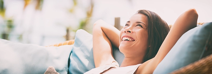 Chiropractic Ocoee FL Happy Woman A smiling woman sitting with her arms behind her head on a couch.
