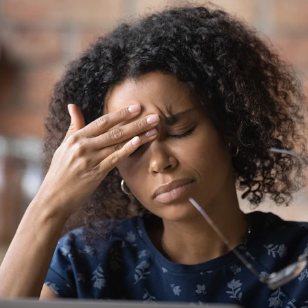 A woman pressing her fingers into her forehead.