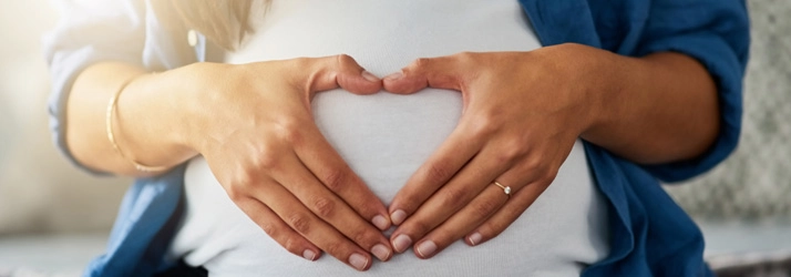 Chiropractic Ocoee FL Pregnancy A pregnant woman making a heart shape with her hands over her belly.